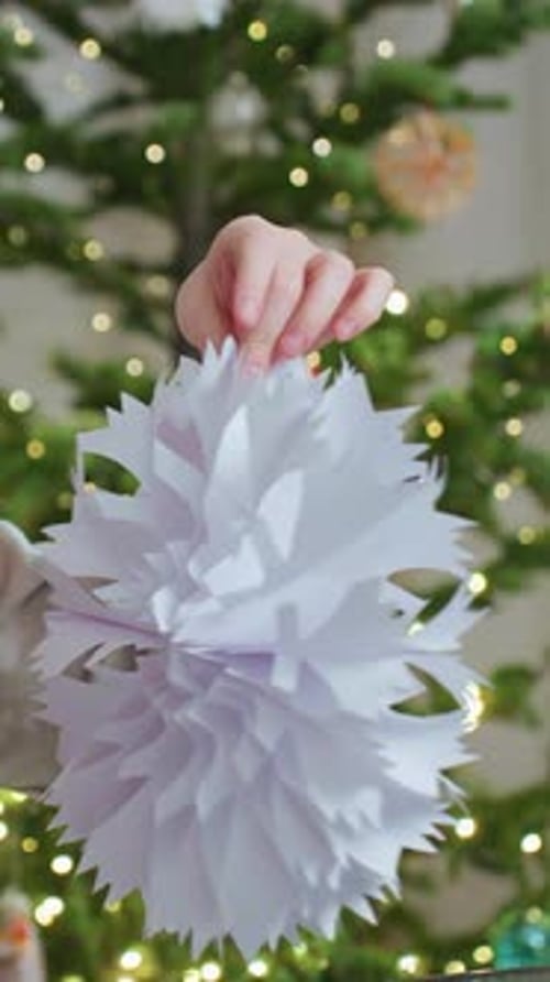 Child Holding Christmas Decoration in Front of Tree