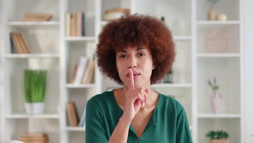Attractive Young Brunette in Green Blouse Showing Shush Sign Indicating Silence
