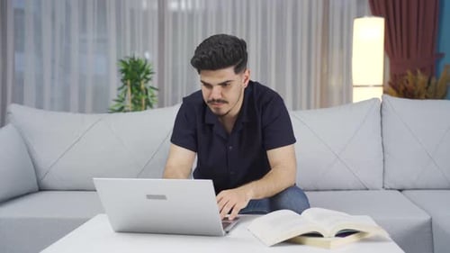 Young Adult Celebrates Success on Laptop at Home