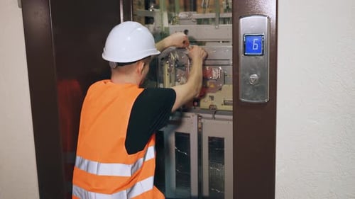 Repairman Working on Elevator Equipment in Building