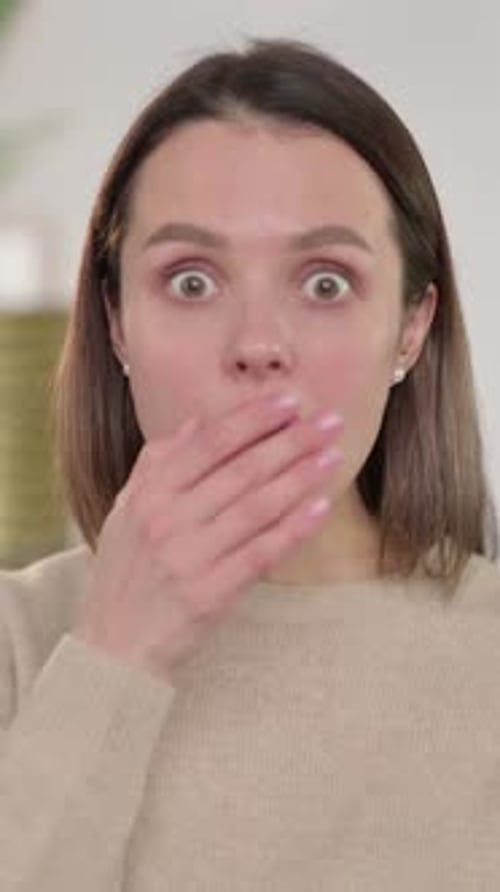 Shocked Woman Covers Mouth Indoors in Vertical Video