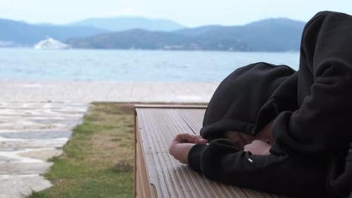 Person Lying On Bench Near Beach