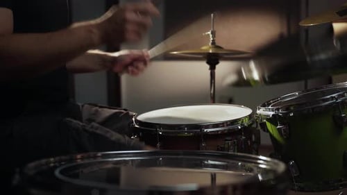 A Drummer's Hands are Shown Hitting a Snare Drum in a Studio Setting The Camera is Positioned Close