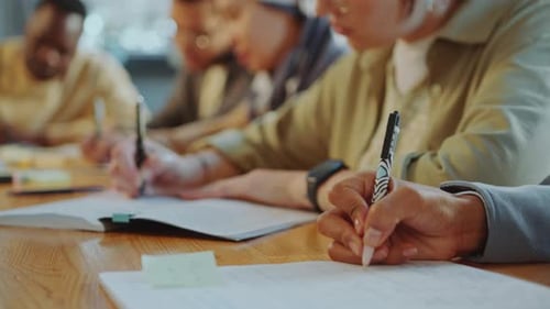 Students Writing in Copybooks at Classroom Desk during Lecture