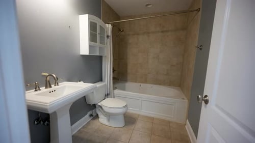 Veraltetes Badezimmer mit Waschbecken, Toilette und Badewanne, das vor der Renovierung abgenutzt war