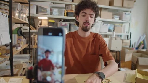 Hombre filmando un vlog de joyería de bricolaje con teléfono inteligente