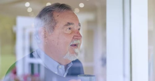 Senior Man Drinks Coffee Looking out Window