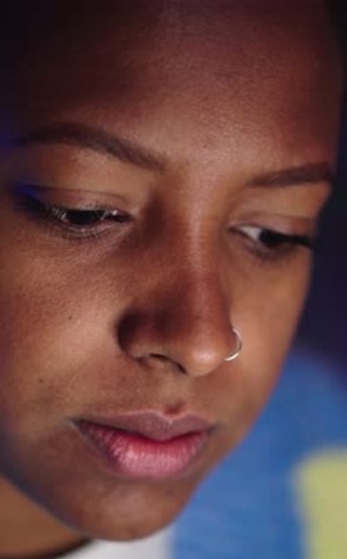 Foto de una joven afroamericana que trabaja hasta tarde usando una computadora portátil en una habitación oscura
