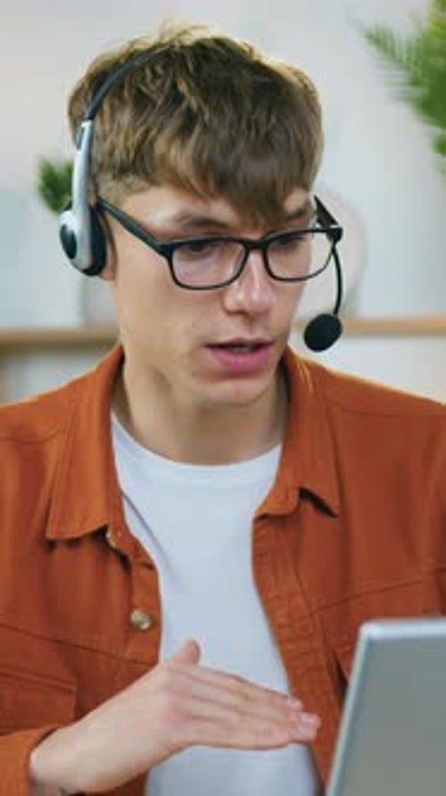 Young Man with Headset Talking at Computer Indoors