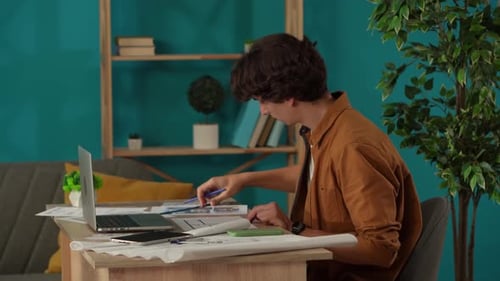 Medium Shot Capturing a Man Working in His Home Office Young Architect Looking Through the Blueprint