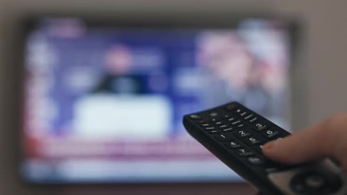 Hand with TV Remote Person Switches Channels Watches TV News and Entertainment Show