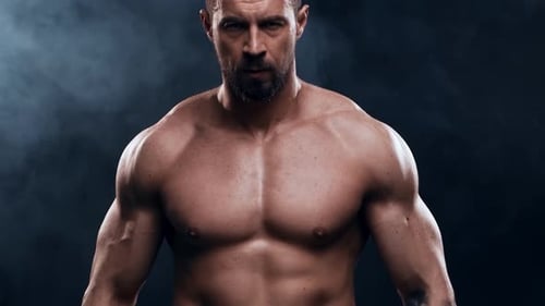 Fisicoculturista en forma y deportivo sobre fondo negro Entrenamiento de culturista con barra El concepto de