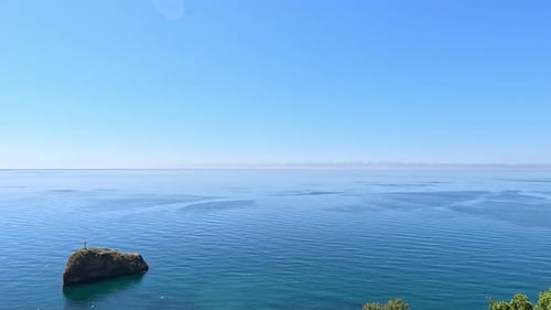 Aerial View on Calm Azure Sea and Volcanic Rocky Shores Small Waves on Water Surface in Motion Blur