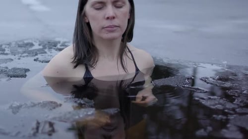 Une femme qui prend un bain de glace joint ses mains et respire calmement. Curseur, gros plan