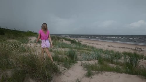 WINDY Blonde Woman in Pink is Running Towards the Sea Before the Storm