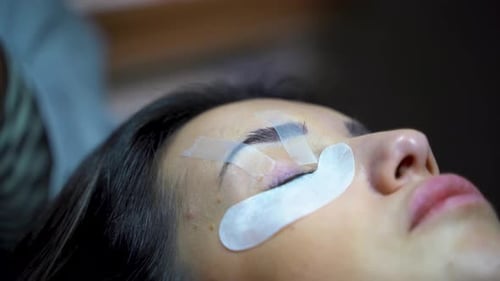Woman with long eyelashes in a beauty salon. Eyelash extension procedure. Lashes close up 4K