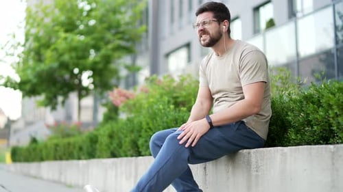 Upset athlete suffers from leg pain, calf muscle spasm during workout sitting on urban city park