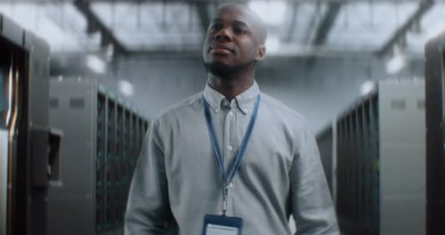 Administrator Walking In Big Data Center with Server Racks Smiling Looking at Camera