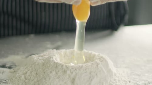 Close-up of Egg Breaking into Flour.
