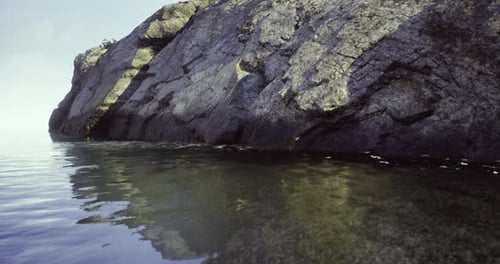 Calm Waters Reflect Rocky Cliffs at Serene Coastal Location During Twilight