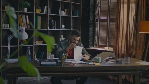 Man Working at Desk Examining Documents in Office