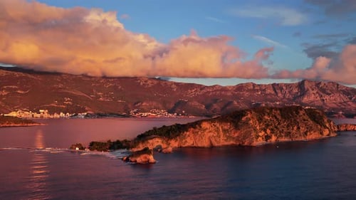 Zumbido aéreo: las montañas brillan con una luz naranja mientras el casco antiguo de Budva se encuentra junto al agua.