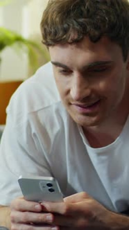 Smiling Man Using Mobile Phone in Home Setting