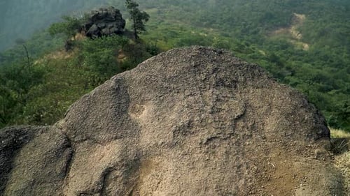 Ariel view of a mountain range in slow motion with beautiful green vegetation on a bright sunny day.