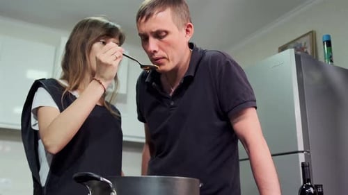 Man and Woman Tasting Food in Home Kitchen
