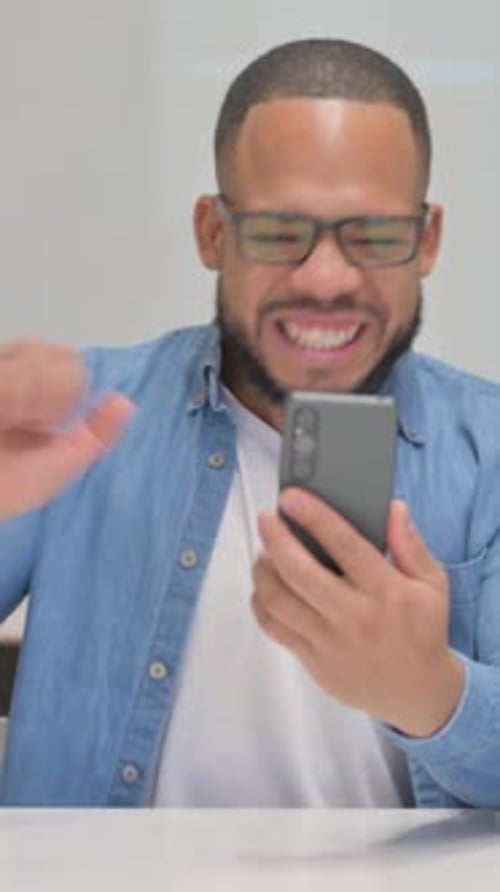 Excited man looking at mobile phone indoors
