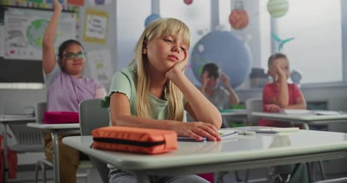 Sad Primary School Girl Sitting at Desk Getting Tired During Lesson or Upset Because of Bad Grade