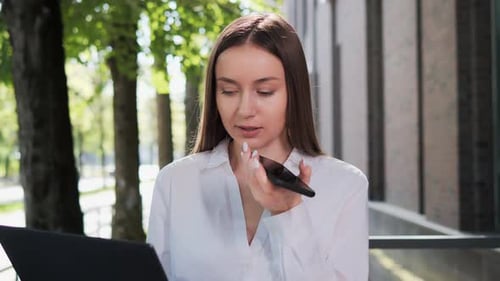 Woman Uses Voice-to-Text on Phone in Urban Area