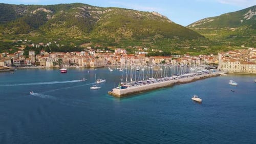 Panorama of a coastal town with many houses with red roofs, surrounded by the sea and mountains with
