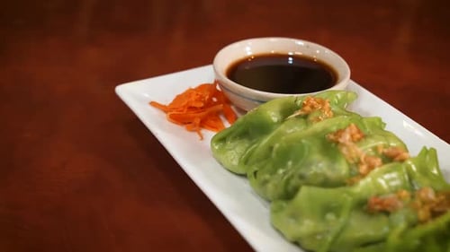 Vegetable dumpling appetizer plate with soy sauce, slider close up 4K