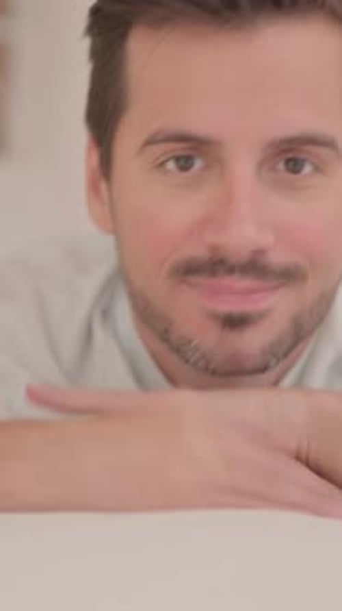 Jeune homme faisant les pouces en l'air alors qu'il est allongé sur le ventre dans son lit, vidéo verticale