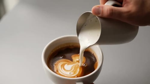 Close Up of Steamed Milk Being Poured Into Espresso Coffee