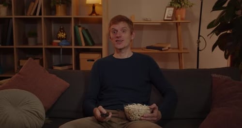 Man Relaxes on Couch with Popcorn, Watches TV