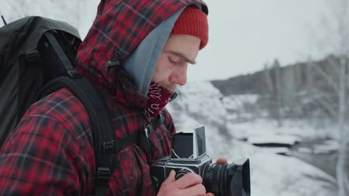 Young Man with Camera in Snowy Winter Landscape