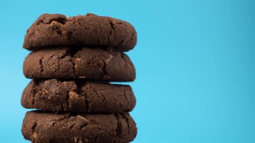 Oatmeal cookies with white chocolate chips rotate on a blue background.