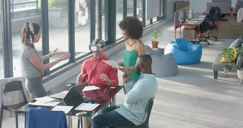 Caucasian businessman wearing vr headset while colleagues watching him at office