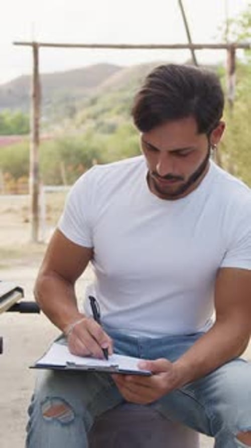 Man Writing on Clipboard Outdoors