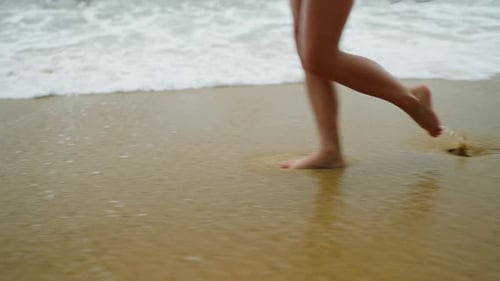 Slim Female Legs and Feet Walking Along Sea Water Waves on Sandy Beach Pretty Woman Walks at Seaside