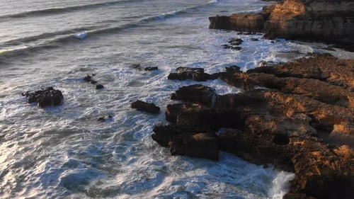 Beautiful aerial drone view of waves hitting the rocky shoreline