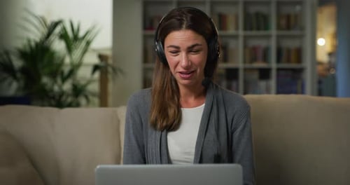 Woman Video Calling Using Laptop and Headphones