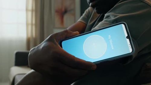 Close Up of Man Scanning CGM Sensor with Phone Displaying Normal Glucose Reading