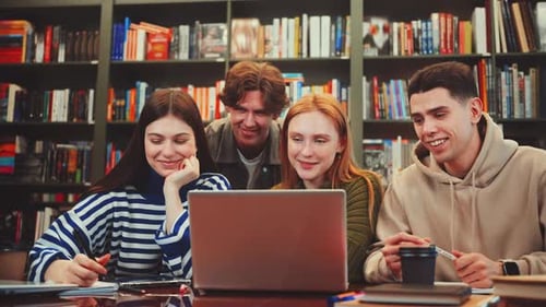 Étudiants collaborant sur un ordinateur portable dans une bibliothèque