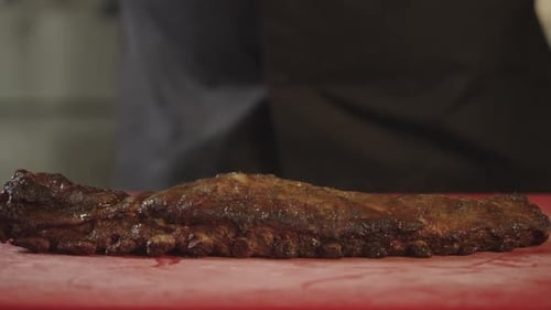 A Professional Chef Puts Barbecue Ribs on a Cutting Board