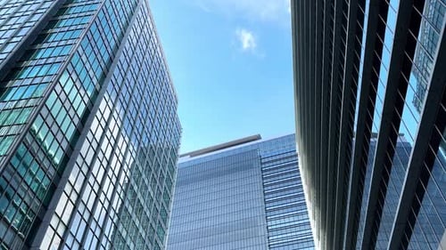 Tall modern skyscrapers with glass facades reflecting a clear blue sky