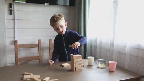 Junge spielt Jenga-Spiel zu Hause mit Mama