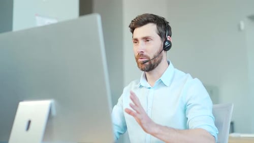 Friendly Man Works with Headset at Computer